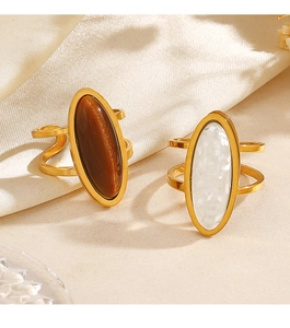 Detailed view of two gold stainless steel rings with oval tiger eye stones on silk fabric