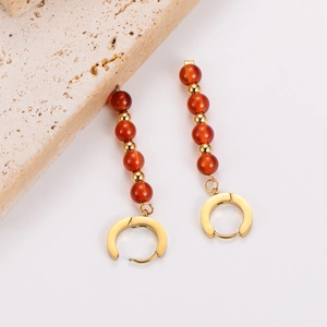 Macro detail of vintage gold drop earrings featuring polished reddish brown beads