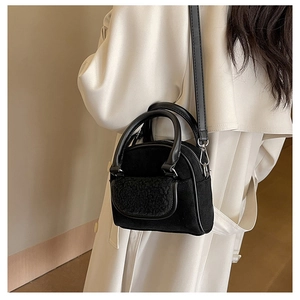 Detail of black suede handbag with plush textured pocket and dual handle strap design