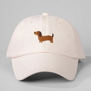 Close-up of light pink baseball cap featuring detailed brown dachshund dog embroidery