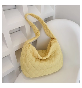 Close-up of yellow quilted cotton shoulder bag with elegant diamond stitching on a white chair