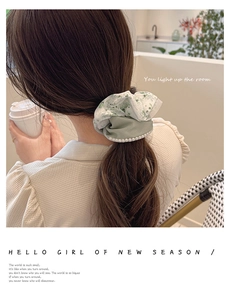 Detail of light green floral lace scrunchie with faux pearl trim and soft texture