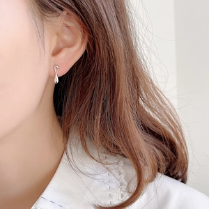 Detailed close-up of a minimalist silver teardrop earring on a model's ear