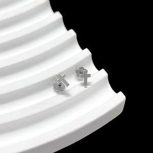 Detail shot of silver cross stud earrings with decorative floral backings on stand
