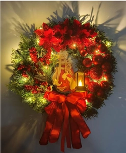Close-up of lighted Christmas wreath with Nativity scene, red berries, and classic bow