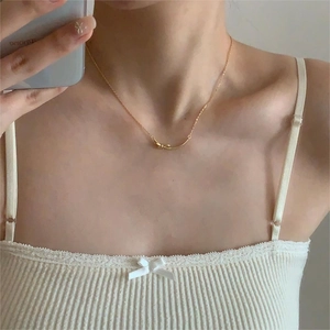 Golden bow pendant necklace styled with white lace dress in a mirror selfie detail