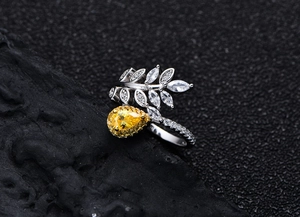 Macro shot of silver ring featuring a yellow pear-cut gemstone and leaf-shaped diamonds