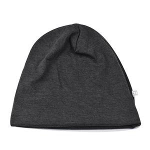 Close-up of the knitted fabric texture and white care label on a dark grey beanie