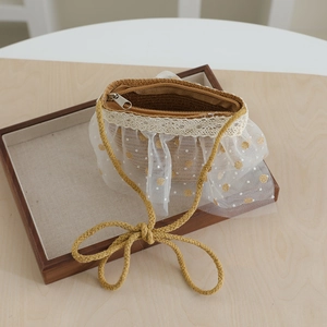 Detail of straw woven crossbody bag with white lace trim and gold polka dot mesh detail