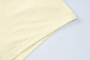 Detail of double-needle stitching on the hem of a cream yellow knitted slim jumpsuit