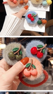 Dettaglio di elastici per capelli in peluche con pompon colorati e ciondoli a forma di ciliegia