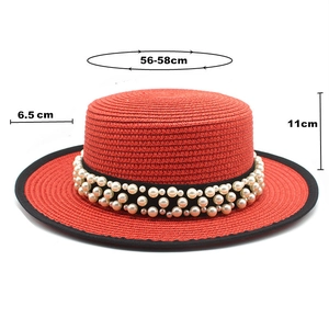 Dettaglio di un cappello di paglia rosso con perle e misure di grandezza precise