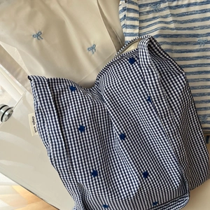 Gros plan du sac en coton à carreaux bleu et blanc avec broderie florale et étiquette texte
