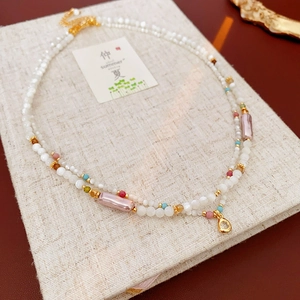 Detailed close-up of double-layer beaded necklace with pearl finish and teardrop pendant