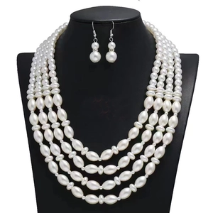 Detail of four-layer faux pearl necklace set with matching earrings on a black bust