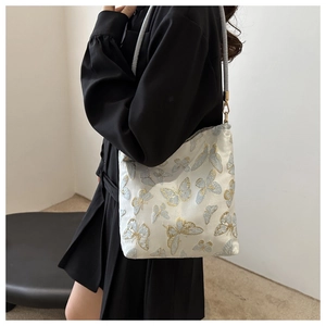 Detail of light blue and gold butterfly embroidery on white silk fabric of a bucket bag