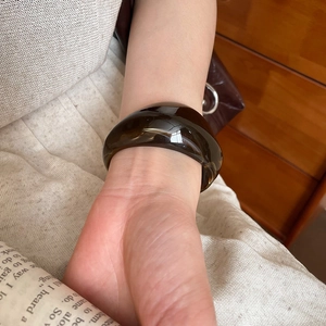 Close-up of a thick amber resin bangle on a female wrist with warm lifestyle aesthetics