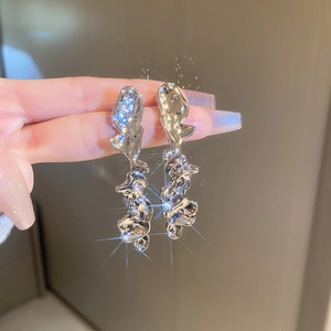 Detail of silver liquid metal style long earrings with irregular aesthetic design