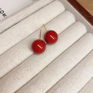 Detail showing red round bead earrings with gold plating in a white fabric jewelry box