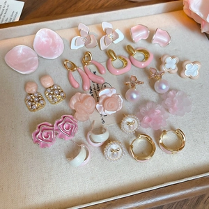 Detailed close-up of pink flower and pearl earrings assortment on a velvet tray