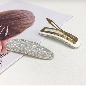Detail showing two pearl and rhinestone hair clips with golden metal structure and backing