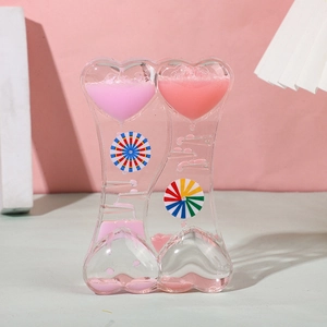 Close-up of heart-shaped liquid timer with pink oil drops and rotating waterwheel