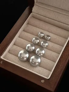Dettaglio di quattro paia di perle grigie graduate in un elegante portagioie in legno