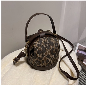 Detailed macro view of leopard print bucket bag with brown leather trim and gold hardware