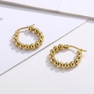 Détails des boucles d'oreilles créoles en forme de U en perles dorées sur fond blanc épuré