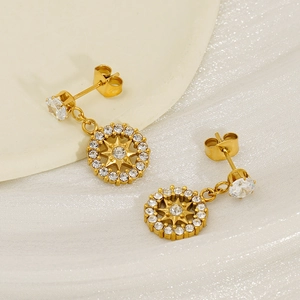 Polished gold flower drop earrings with sparkling zircon crystals on white fabric