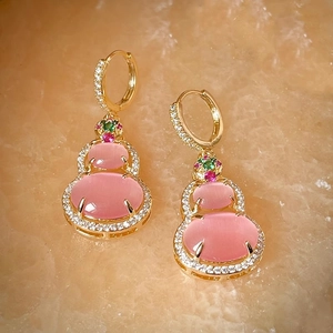 Macro shot of 14k gold-plated gourd earrings with pink cat's eye stones and zircons