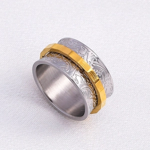Two-tone spinner ring with engraved floral patterns and a gold geometric rotating band