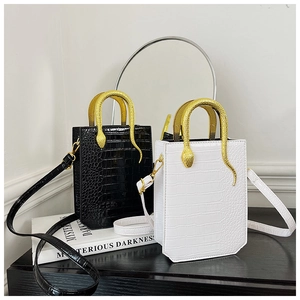 Detail of mini crocodile pattern handbags featuring unique gold snake-shaped handles