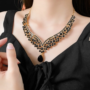 Detail of vintage V-shaped gold necklace with black rhinestones and teardrop pendant on neck