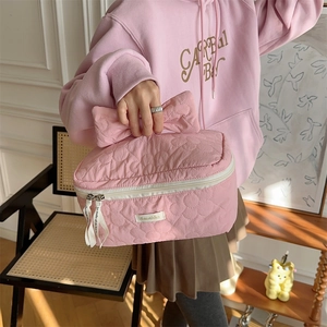 Détail de la trousse de maquillage matelassée rose avec broderie florale et nœud