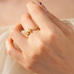 Nahaufnahme eines goldenen Vintage-Rings mit Zirkon-Blumen am Finger getragen