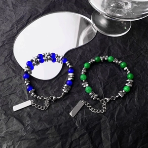 Detailed close-up of blue and green cat eye bead bracelets with silver accents on black