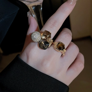 Close-up of gold-plated rings with brown and grey crystals worn on hand by a model