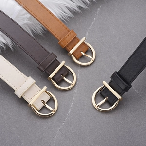 Flat lay of four leather belts in black, brown, and cream with gold D-buckles on marble