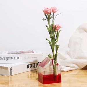 Dettaglio macro di un vaso in resina a forma di casa con rose rosa su tavolo in legno