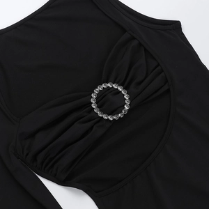 Close-up of sparkling round rhinestone buckle on black slimming knitted dress waist