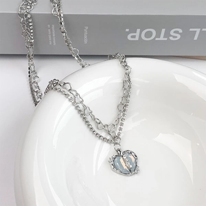 Detailed macro view of heart pendant with lightning crack pattern on layered silver necklace