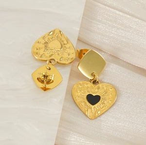 Détail de boucles d'oreilles cœur doré avec gravure rayons et centre cœur noir