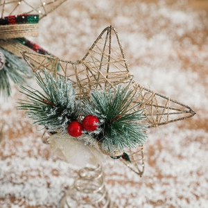 Golden jute fiber star tree topper with red berries and pine needles on snow background
