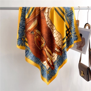 Detail of luxury silk scarf showing yellow saddle print and blue tassel border details