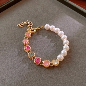 Detail of multi-color crystal and pearl split chain bracelet on gray velvet surface