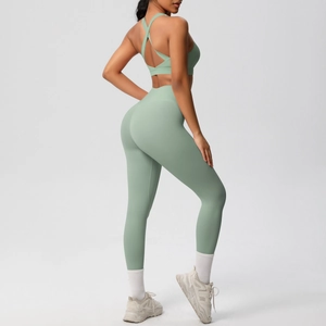 Detalle del sujetador de yoga con espalda cruzada y leggings en tela elástica verde