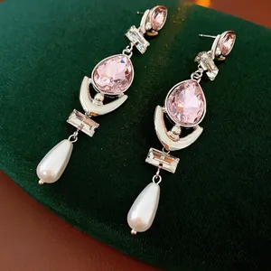 Vintage silver stud earrings with pink drop crystal and white pearl pendants on green velvet