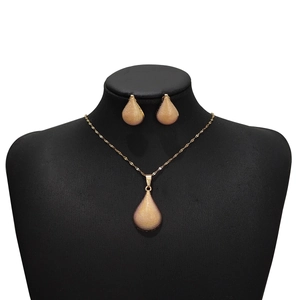 Detail of golden teardrop jewelry set with mesh texture on a black display bust