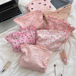 Detail of pink quilted cosmetic bags with floral and rabbit patterns on white bedding